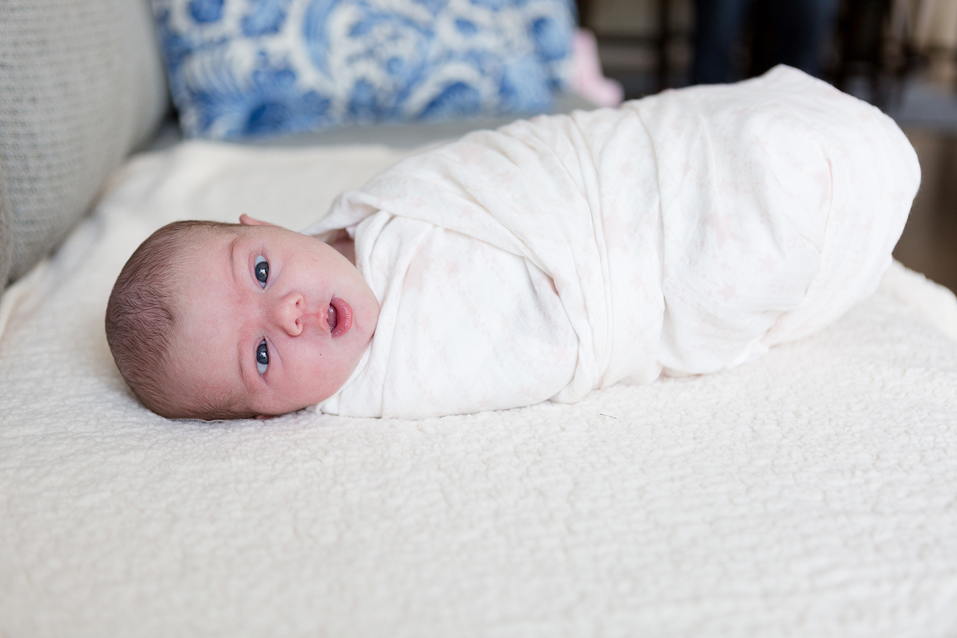 a baby lays swaddled on a bed