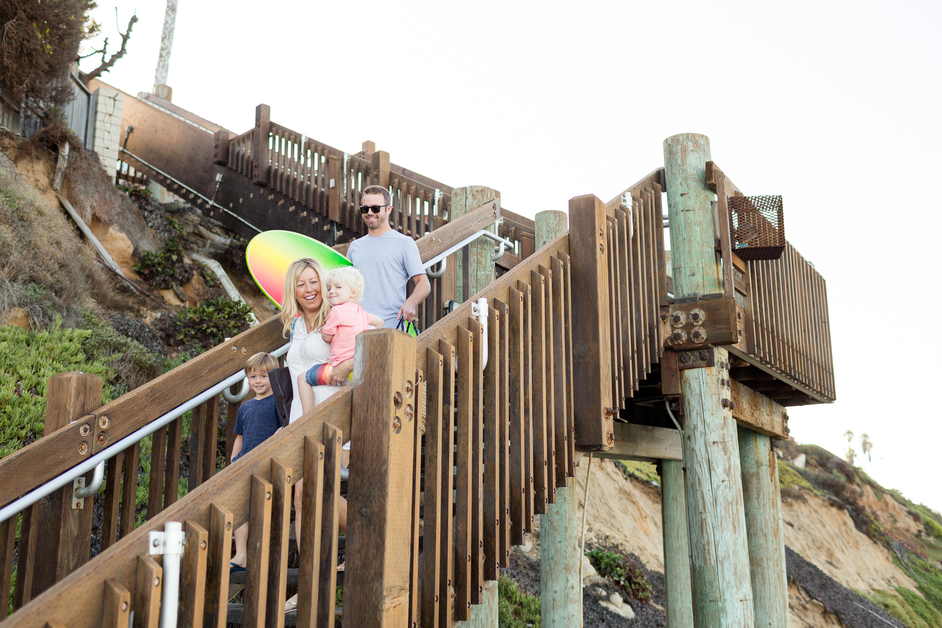 a family walks down the stairs at grandview beach in Encinitas, CA