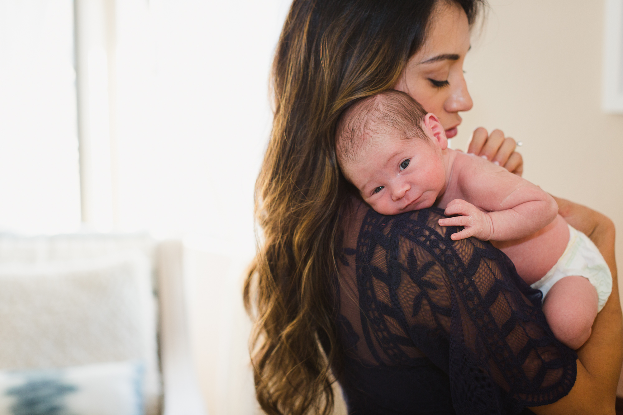 a mom holds her newborn baby against her shoulder