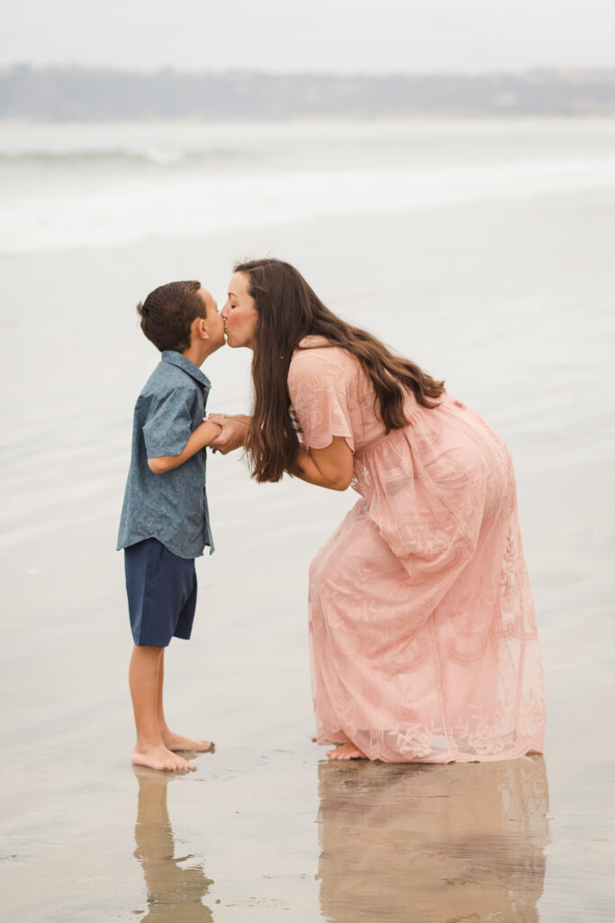 Mom and son posing for family photographer on the beach