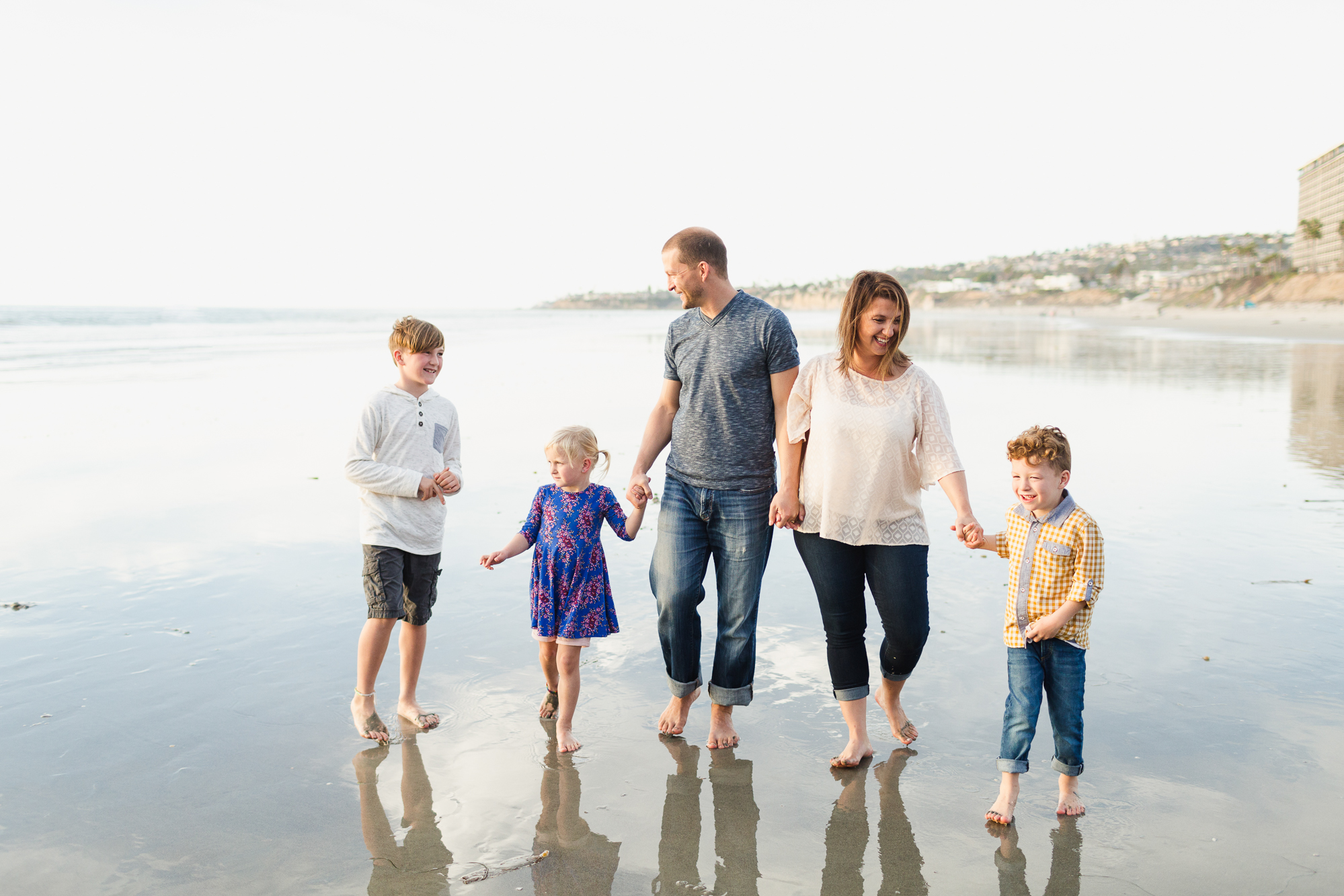 Family of five walks together on the beach in San Diego during their family photography session.