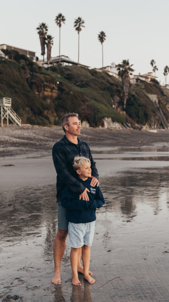 Dad and son standing on the beach together