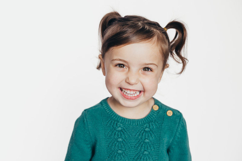 Smiling young child with pigtails in studio portrait, ideal example image for GotPhoto for preschool photography gallery or school picture day system.