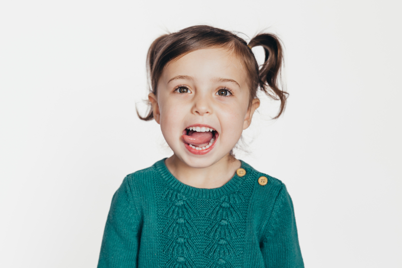 Smiling young child with pigtails in studio portrait, example image used with GotPhoto for preschool photography gallery and school photo ordering system.