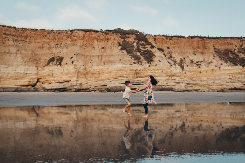 Kids playing near shoreline cliffs at one of the best beaches in San Diego, fun candid beach moment