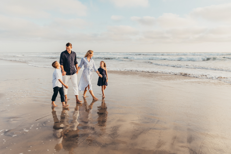Family walking along shoreline at one of the best beaches in San Diego, soft light candid moment