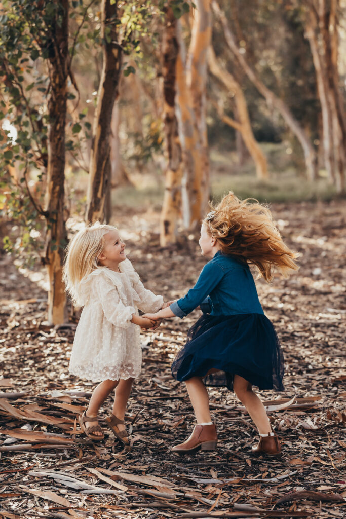 Two children playing together in woods during photography mini sessions, soft light and natural connection
