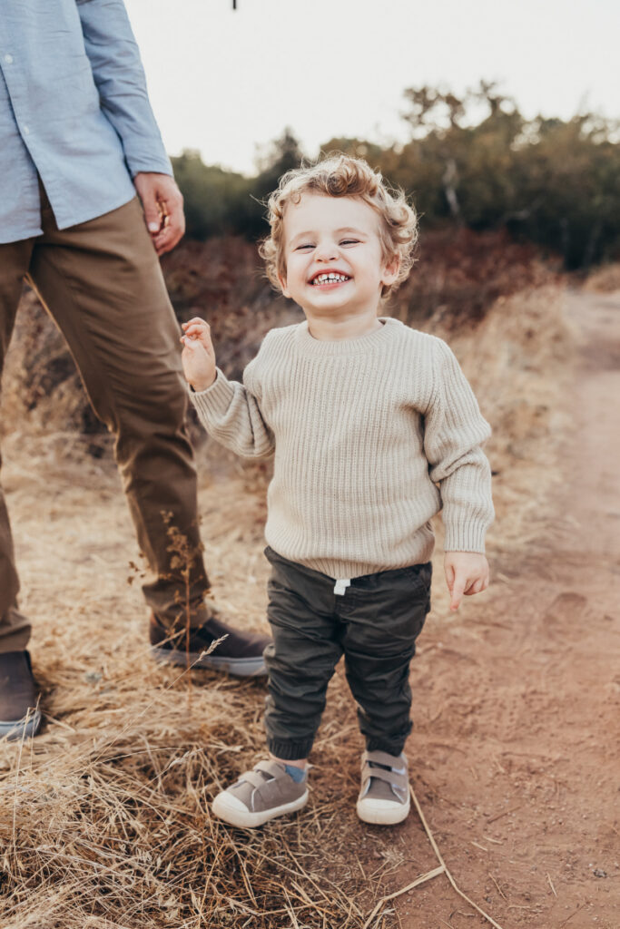 Smiling child walking outdoors during photography mini sessions, capturing playful, relaxed family moments