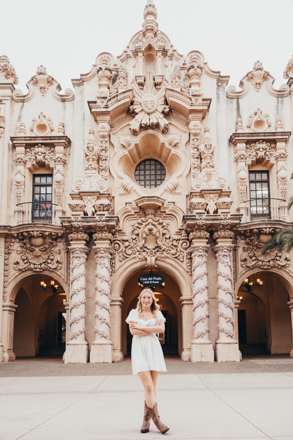 A young woman stands confidently in front of an ornate historic building with intricate architecture and soft neutral tones. This portrait captures the storytelling style and location creativity often explored when learning how to start a photography business and build a memorable portfolio.