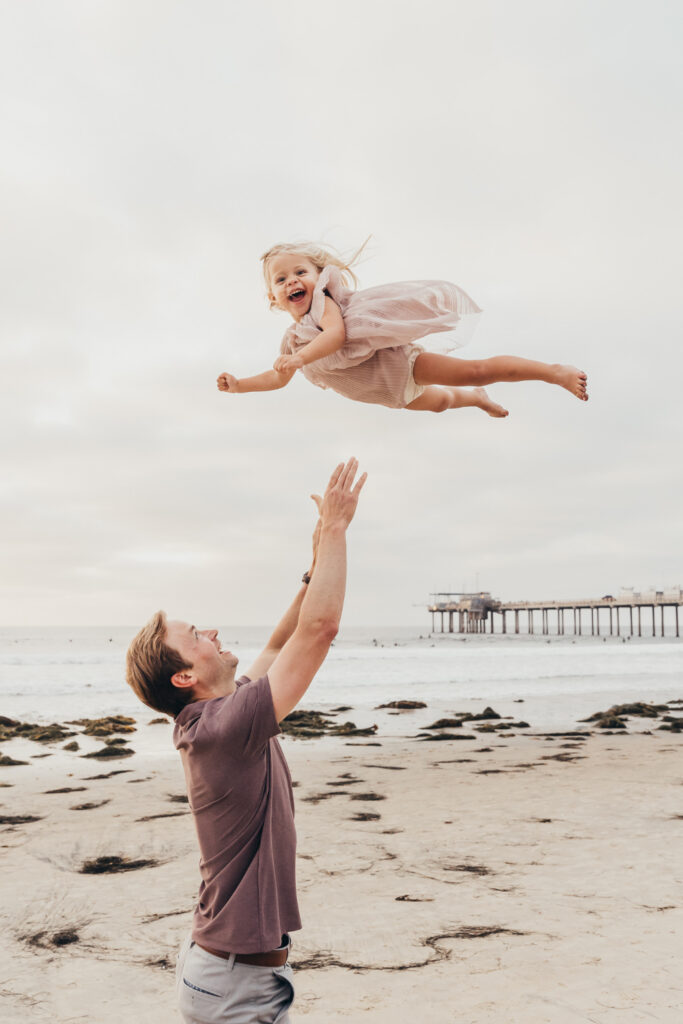 Happy child tossed into the air during a family session, showing how to get referrals through joyful photography.